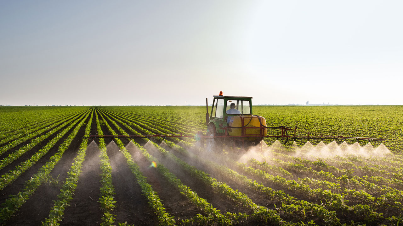 Tractor spraying fertiliser on crops in a field