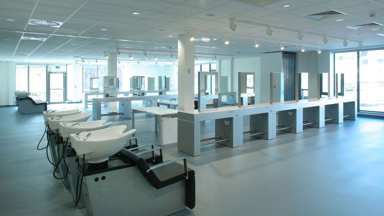A modern salon training space featuring multiple hair washing stations and styling mirrors