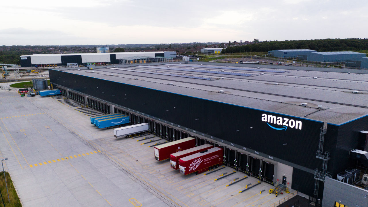 Aerial view of an Amazon distribution center featuring loading docks and delivery trucks parked outside