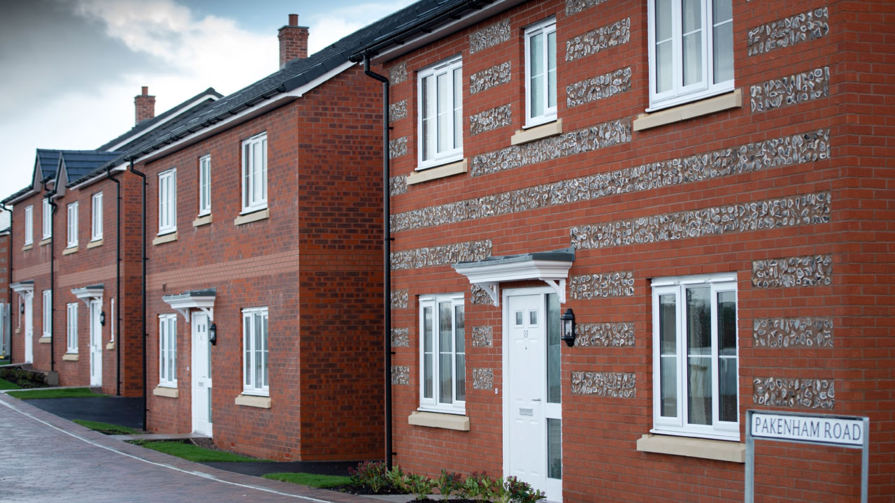 A row of modern brick houses with decorative stone accents and a street sign for Pakenham Road