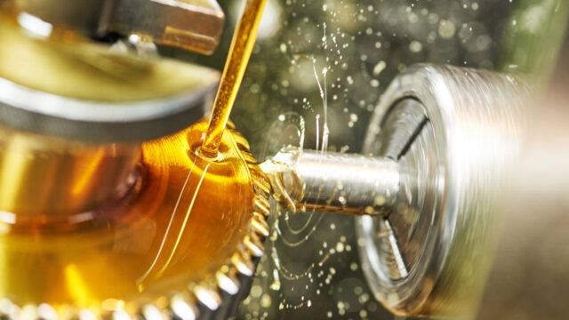 Oil being poured on metal cogs during a manufacturing process