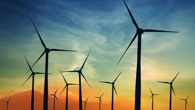 Wind turbines on hill with sunset behind