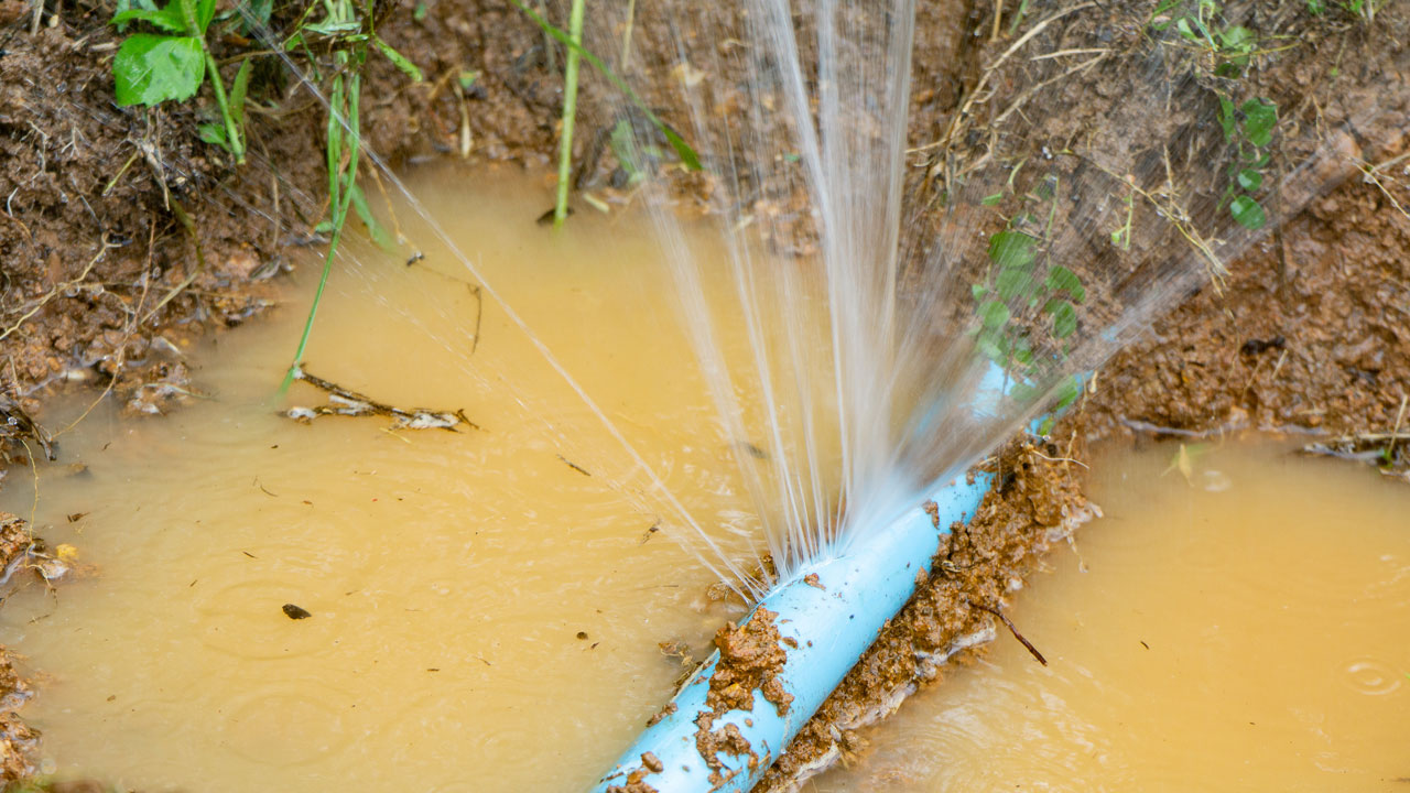 A close up of a leaking water pipe surrounded by flooding