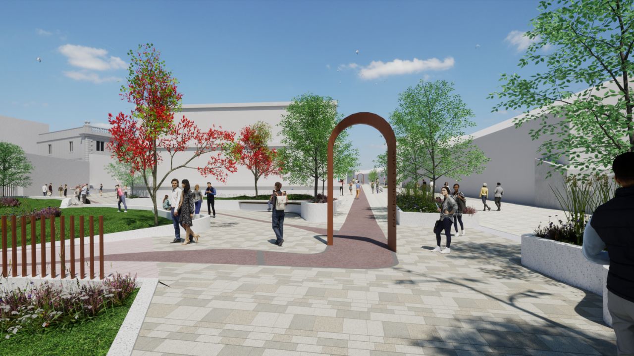 A digital rendering of an urban park walkway with paved paths, green lawns, trees with green and red leaves, a rust-coloured metal archway, and people walking and socialising under a clear blue sky