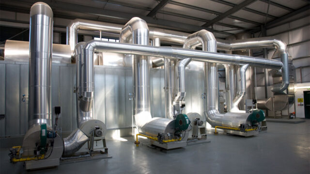 An industrial ventilation system featuring large metal pipes, ductwork, and associated machinery