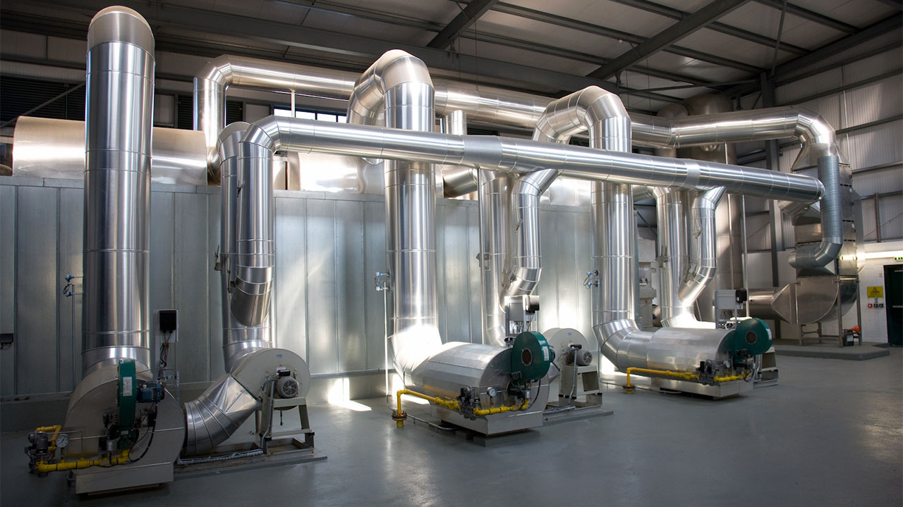 An industrial ventilation system featuring large metal pipes, ductwork, and associated machinery