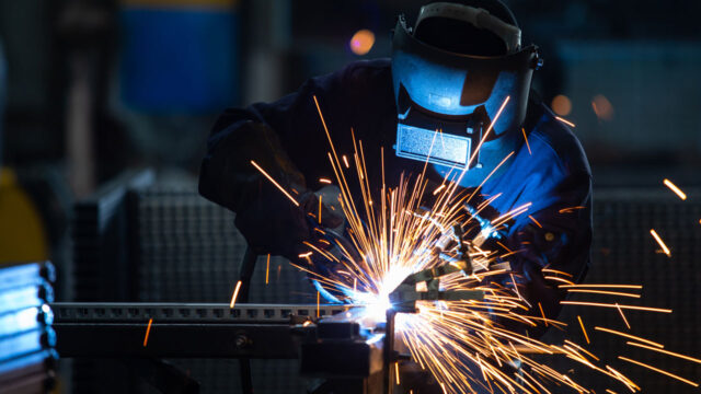 Welder in full protective mask welding a joint