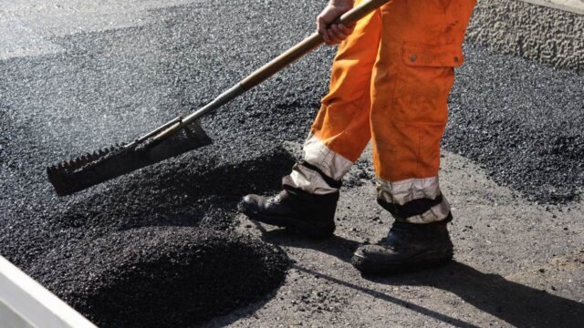Construction worker laying asphalt on a road