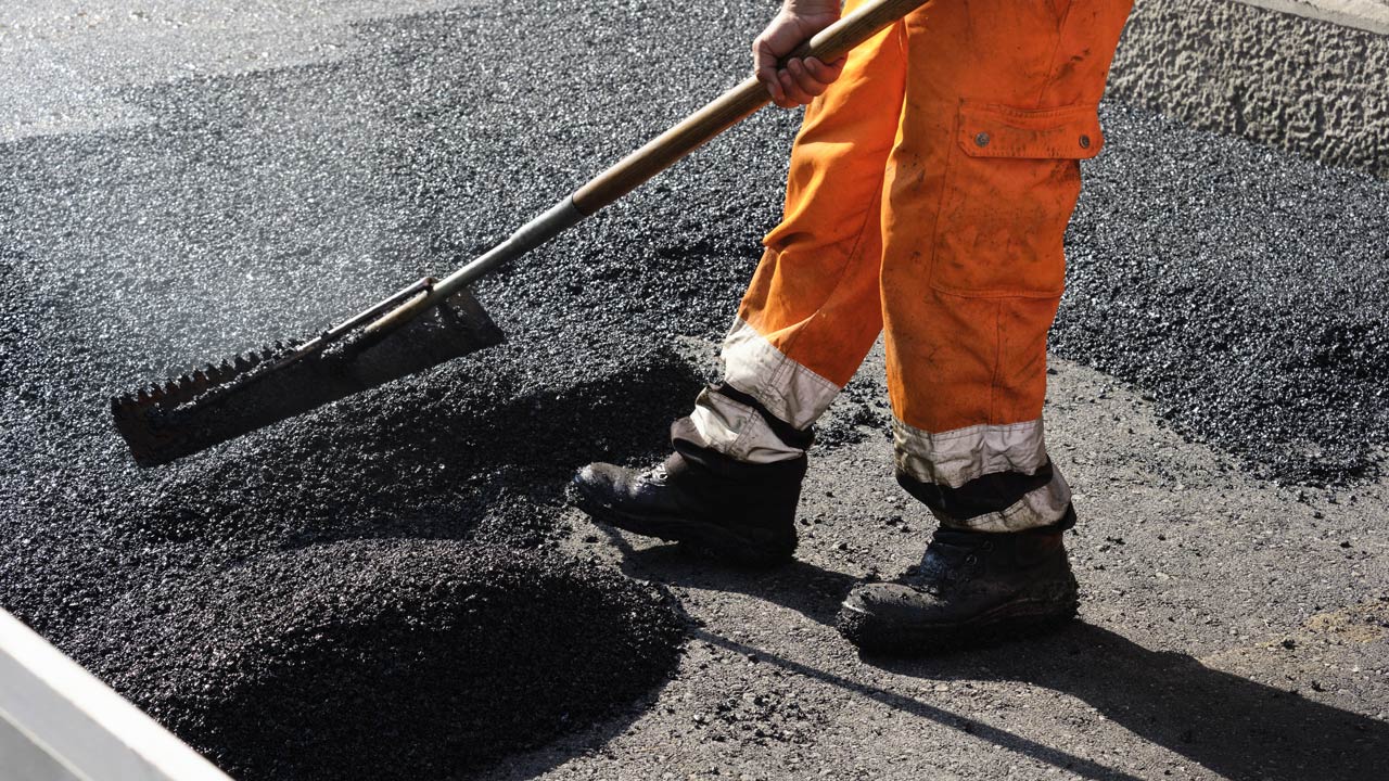 Construction worker laying asphalt on a road