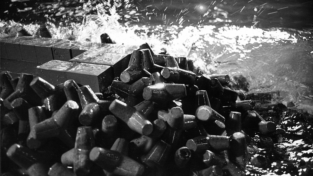 Waves crash against a model coastal wall and rip rap in the Tetra Tech wave lab