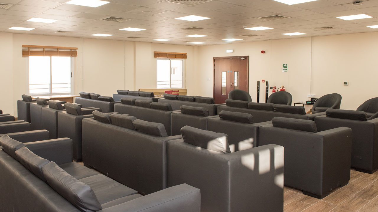 Rows of black armchairs under fluorescent lights
