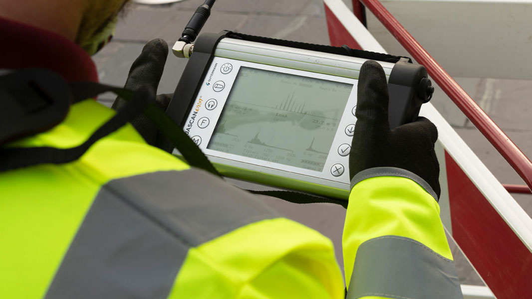 Engineer in high-visibility jacket checking a handheld digital device