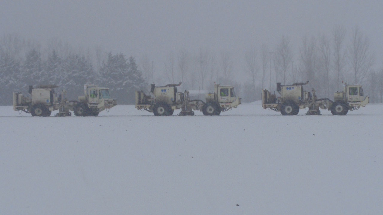Trucks carrying seismic surveying equipment lined up in a snowy landscape