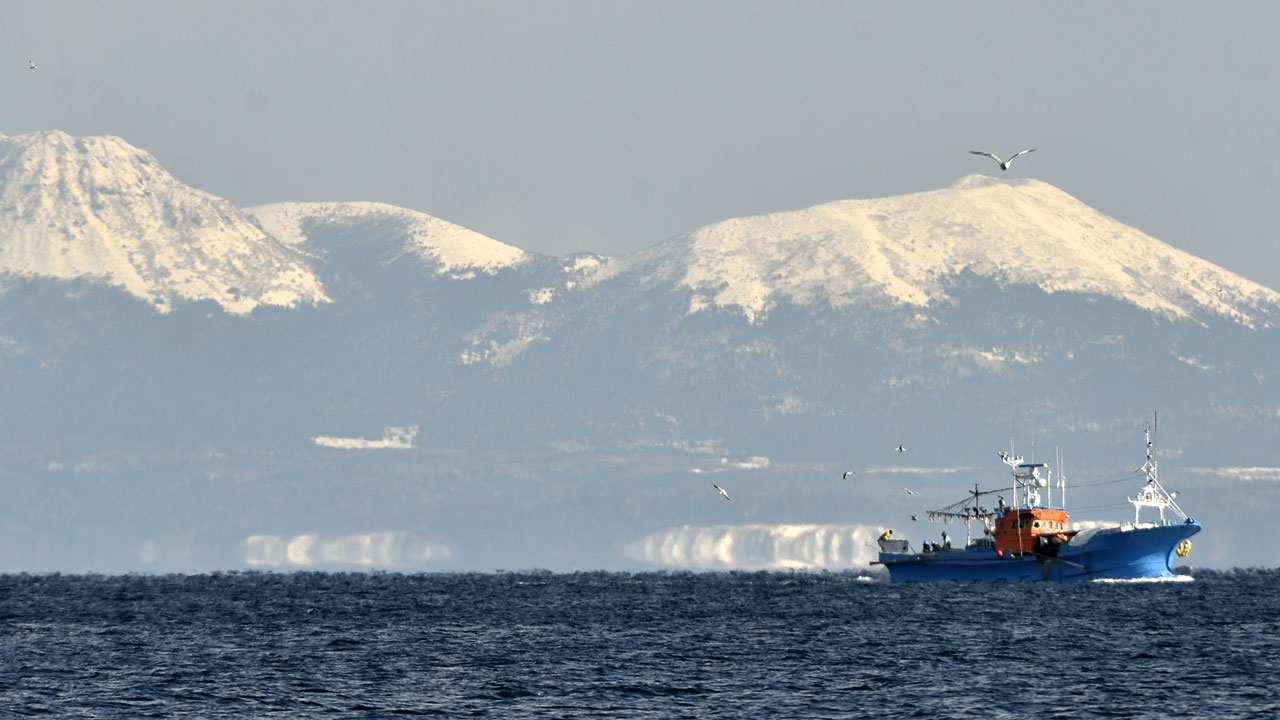 Fishing boat on the sea with snowy mountains in the background