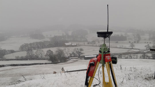 Geospatial survey gear pointed at a snow-covered landscape