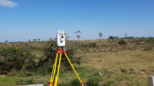 Geospatial survey gear on a tripod pointed at an empty field