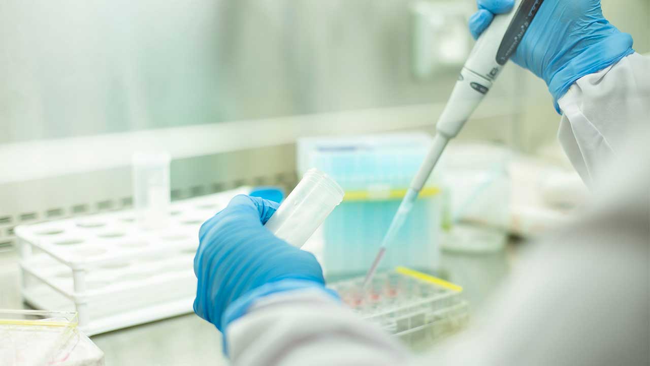 Laboratory worker using test tube sampling equipment in a lab setting