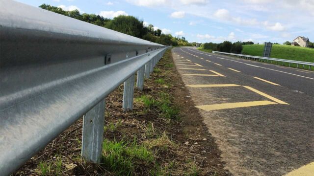 A metal guardrail running alongside a paved road