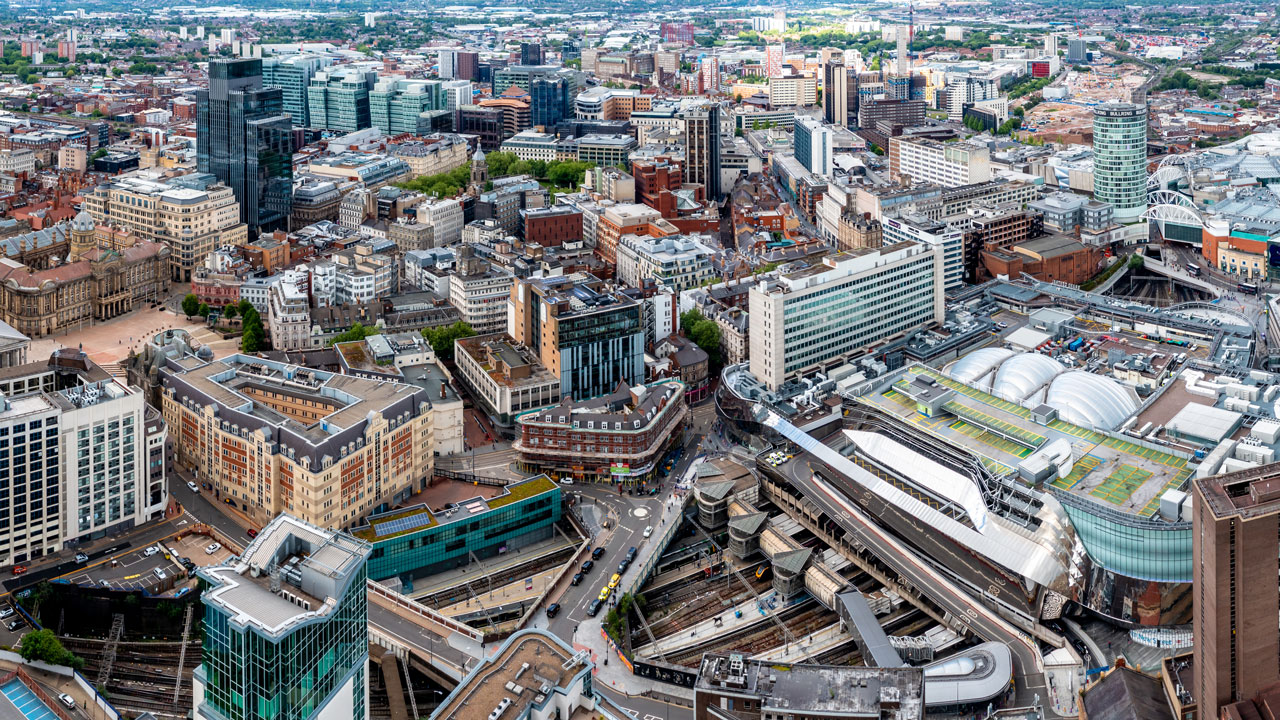 Aerial view of a dense city center with mixed modern and historic buildings and a rail station