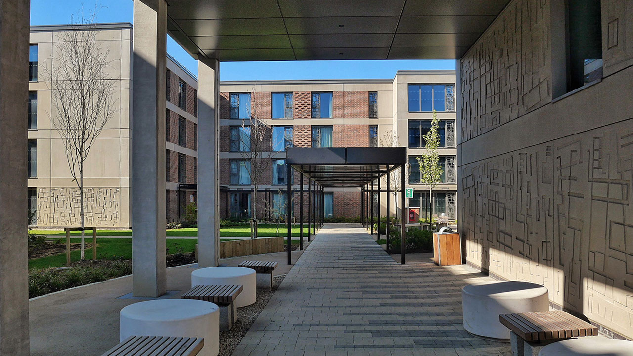 Photo of an outdoor common area on the University of York campus with benches and tables under an open canopy