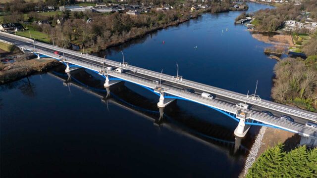 Aerial view of a bridge spanning a river with cars crossing