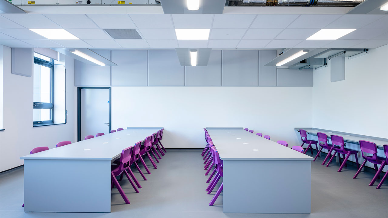 Render image of a room in a school with several large modern tables and purple chairs