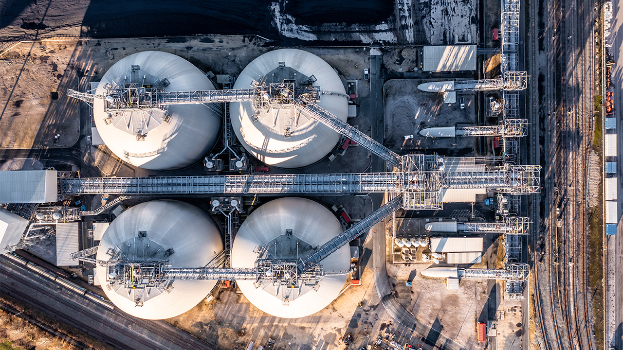 Aerial view of large industrial storage tanks connected by metal gantries and pipework