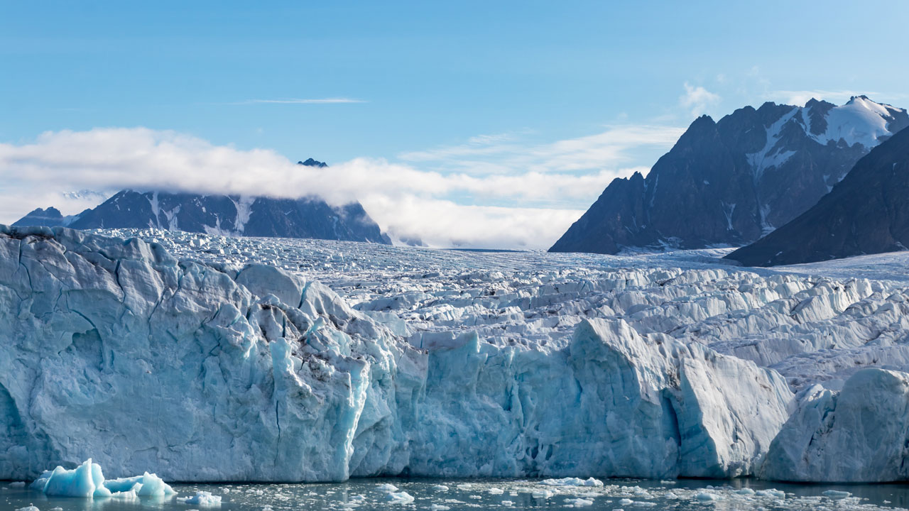 A view of the edge of an ice sheet in an arctic landscape with the sea in the foreground