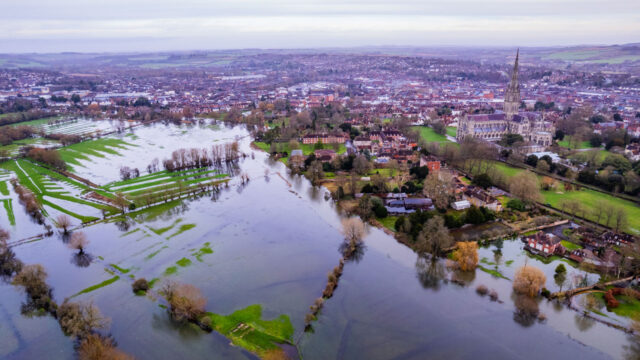 Aerial shot of flooded fields and burst river near a built up residental area