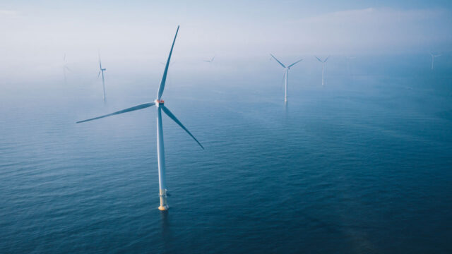 A misty aerial view of offshore wind turbines against the sea