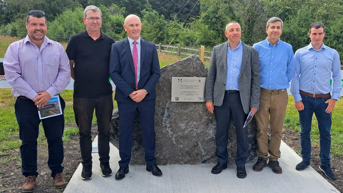 Six members of the project team gathered around an opening commemoration plaque