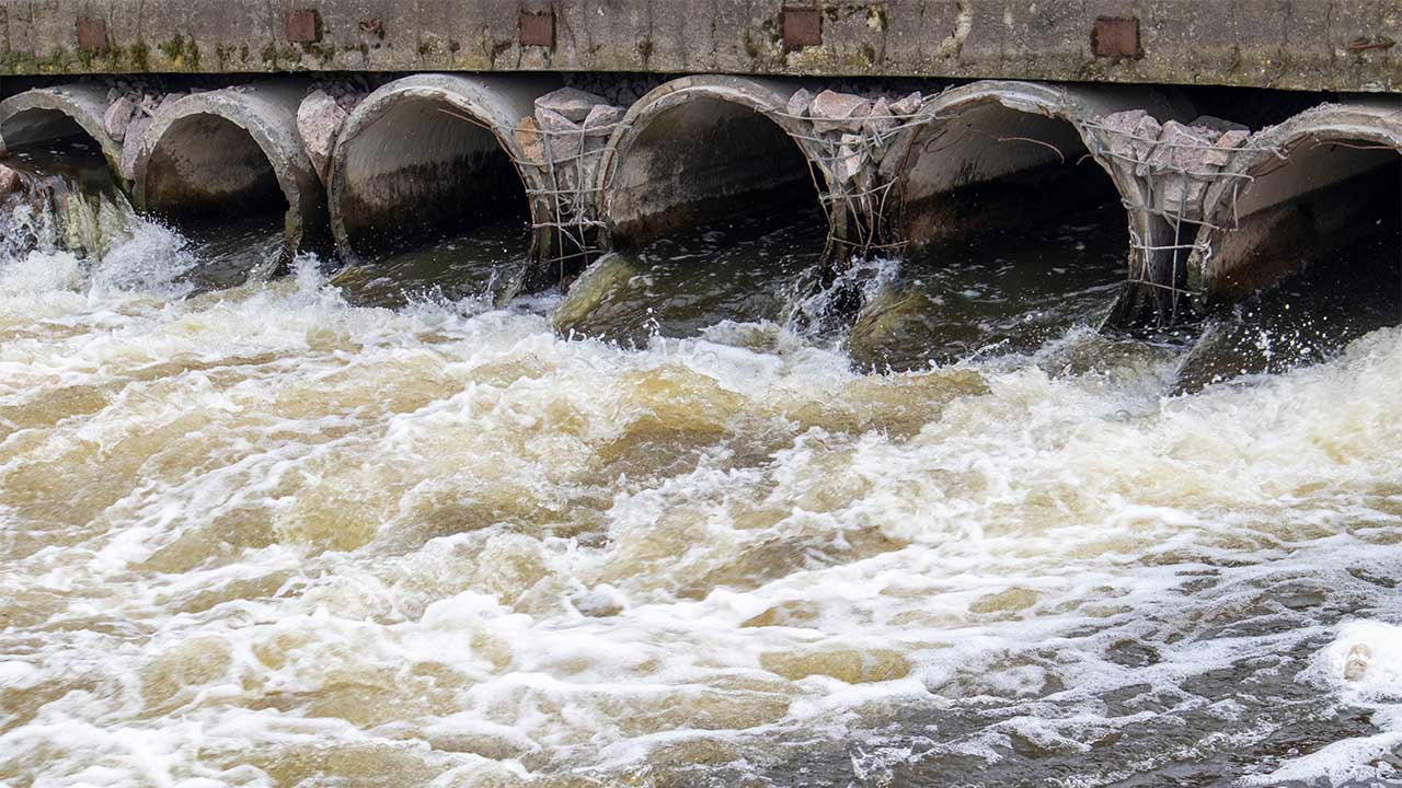 A series of wastewater pipes discharging water into a river