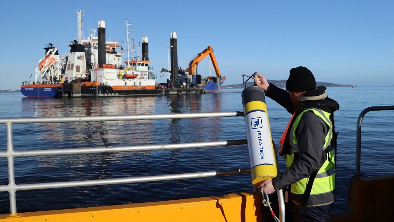 Crew member of deck of boat holding a monitoring tank, with marine platform in background
