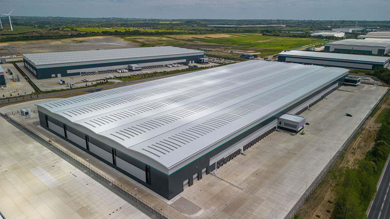 Aerial view of large warehouse building with loading bays along one side and multiple similar buildings behind