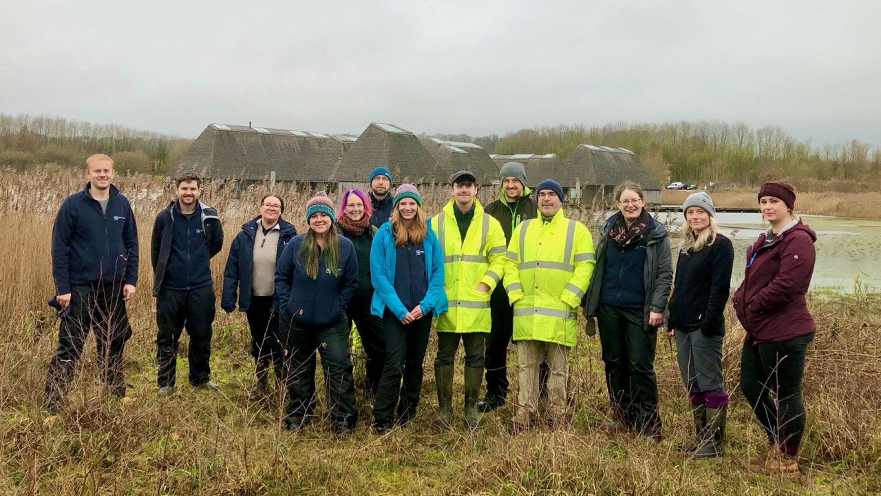 A group of fifteen people standing outdoors in a natural setting