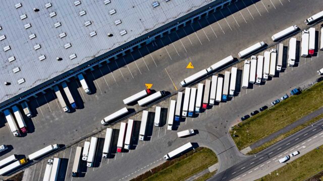 Aerial photograph of transport trucks lined up outside a huge warehouse