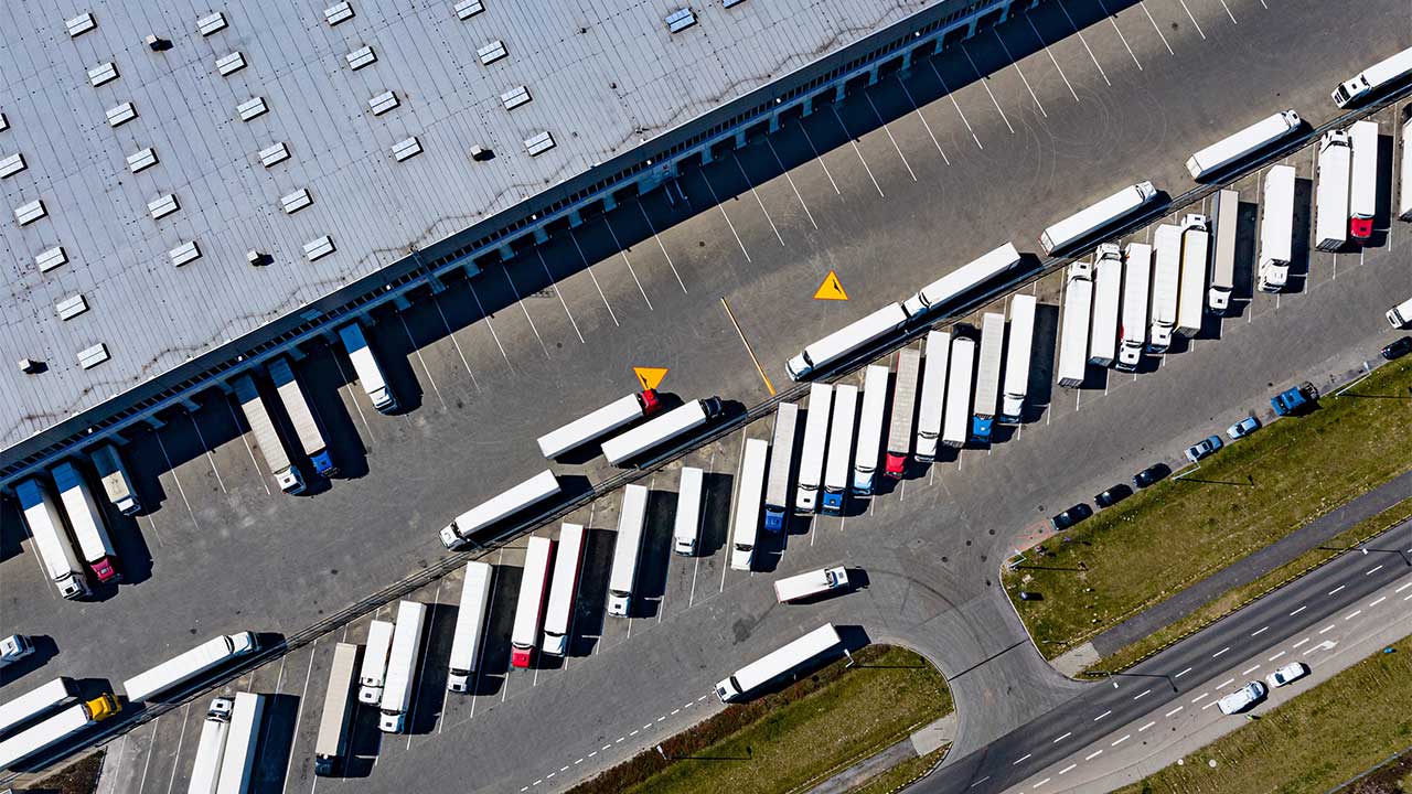 Aerial photograph of transport trucks lined up outside a huge warehouse