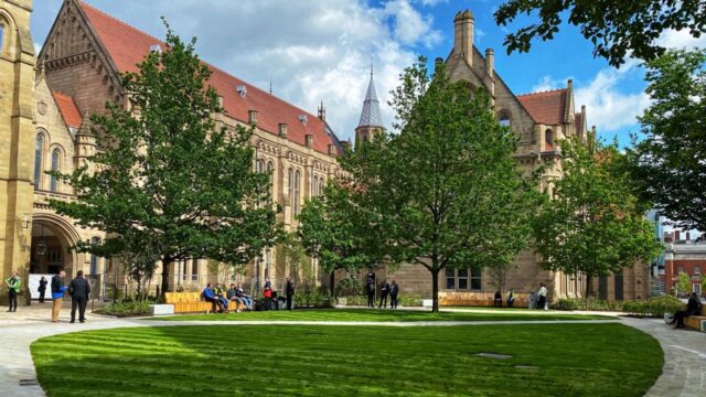 Green lawned area with historic gothic buildings on two sides