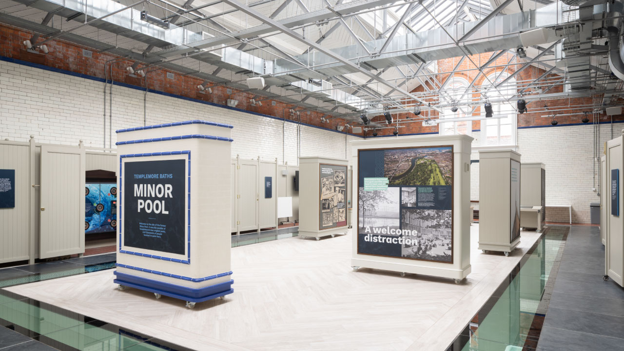 Interior view of an exhibition space featuring informational displays and changing rooms, with a bright and airy atmosphere