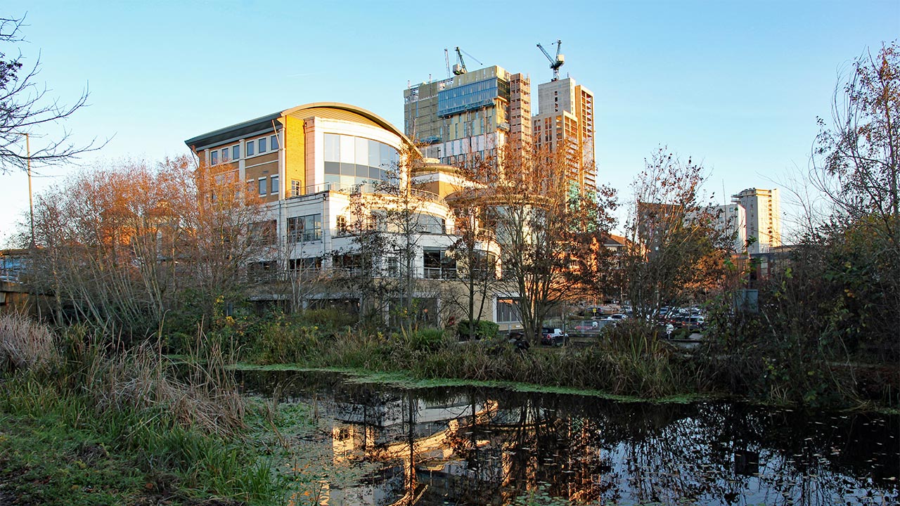 A view across the river in Working towards office buildings with an office block under construction in the distance