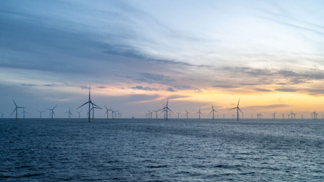 Offshore wind turbines against a stormy sky at sunset