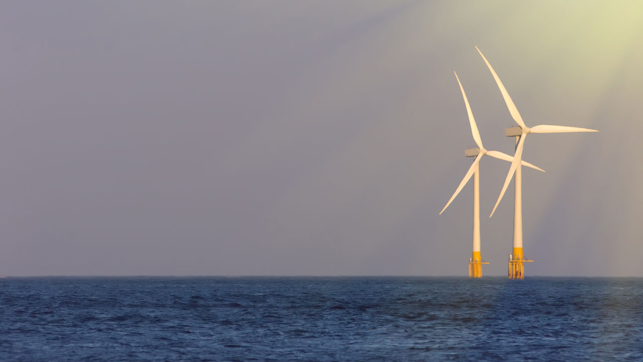 Two wind turbines in the sea caught in a ray of sunshine