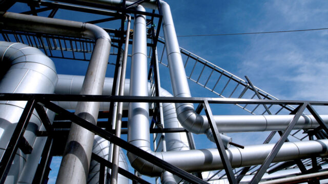 Large metal pipe going in different directions against a blue sky