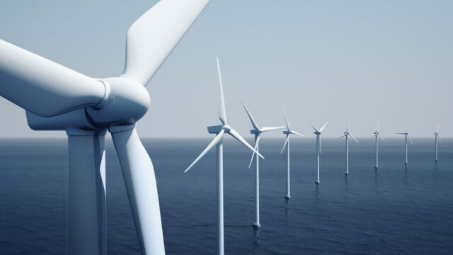 Close up of wind turbines in a line with sea and horizon behind