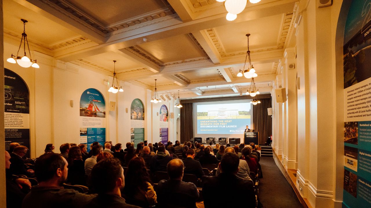 An interior view of a large audience attending a documentary film launch event titled “Unearthing the Heat Beneath Our Feet.”