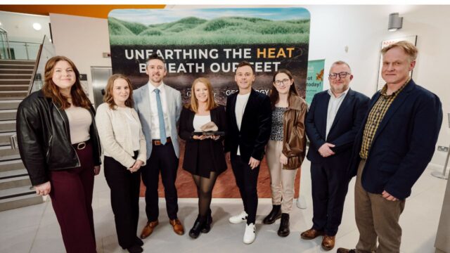 A group photo of eight individuals standing together in front of a banner that reads “Unearthing the Heat Beneath Our Feet.”