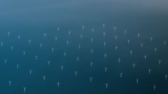 High level aerial view showing wind turbines against the sea