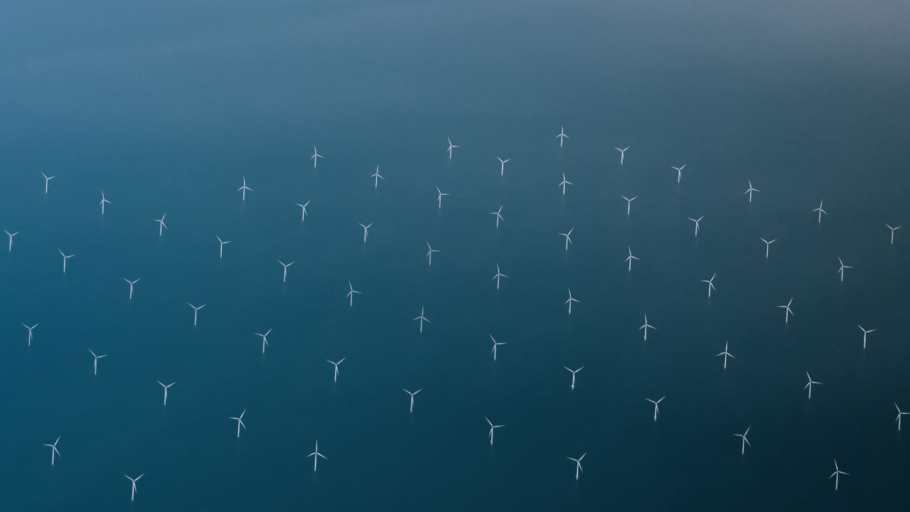 High level aerial view showing wind turbines against the sea