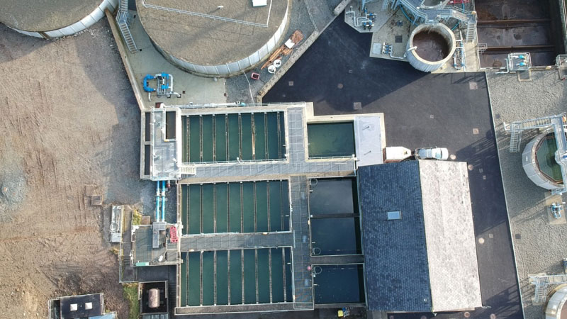 An aerial view of round and rectangular water treatment tanks and control buildings