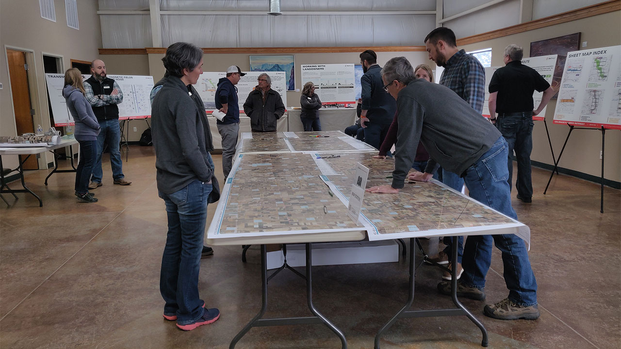 Photo of several people looking at large documents and maps laying on several tables